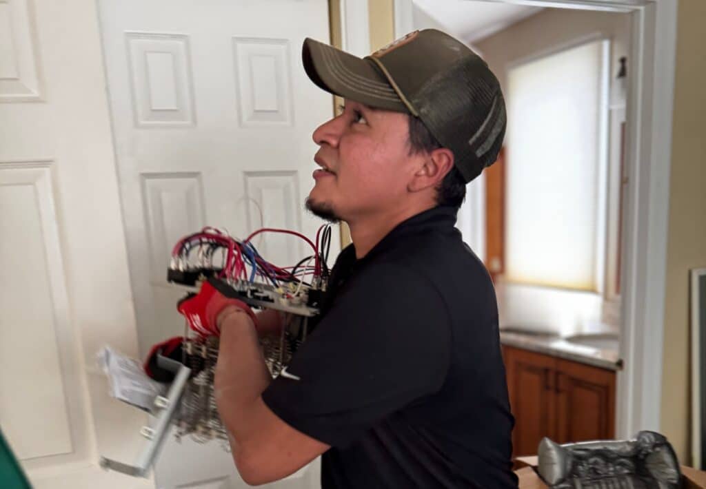 A SwiftPro technician carrying an electric heat strip assembly through a Northern Virginia home