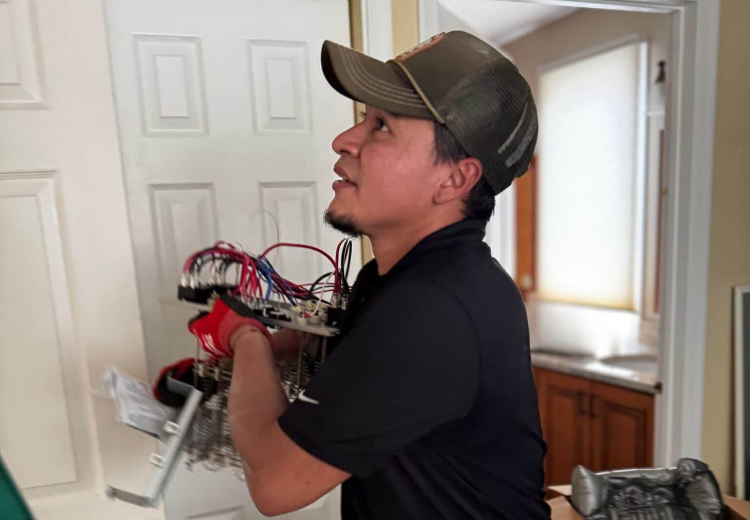 A SwiftPro technician carrying an electric heat strip for a heat pump air handler into a Northern Virginia home