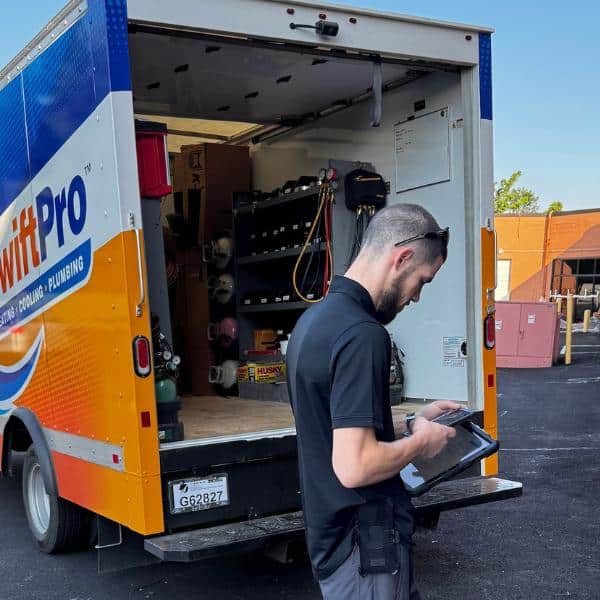 SwiftPro HVAC and plumbing service truck with technician using tablet, providing emergency and preventive care