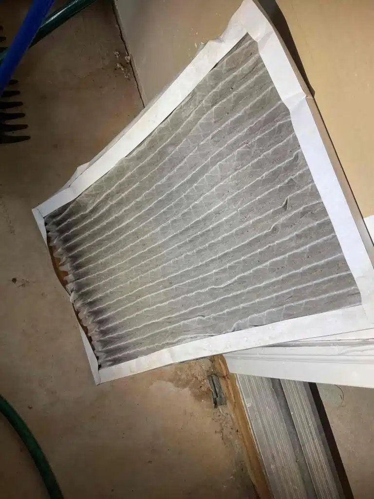 A dust-loaded return-air filter removed from a home's HVAC system and resting on the floor.
