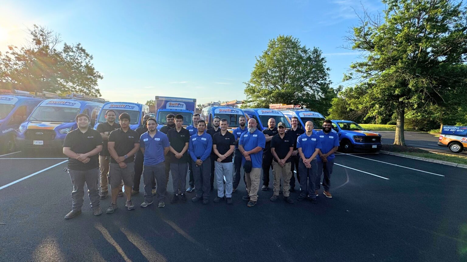 The SwiftPro plumbing and HVAC crew standing with their wrapped service vans in Northern Virginia