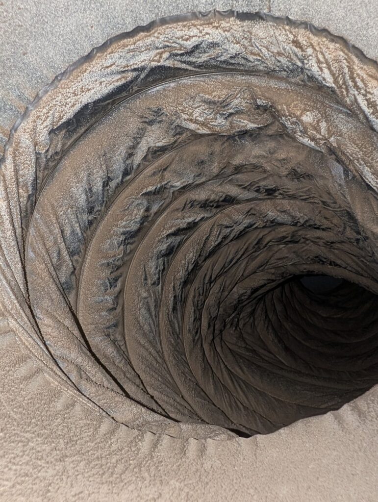 The inside of a flexible duct in a Northern Virginia home, coated in a thick grey layer of dust.