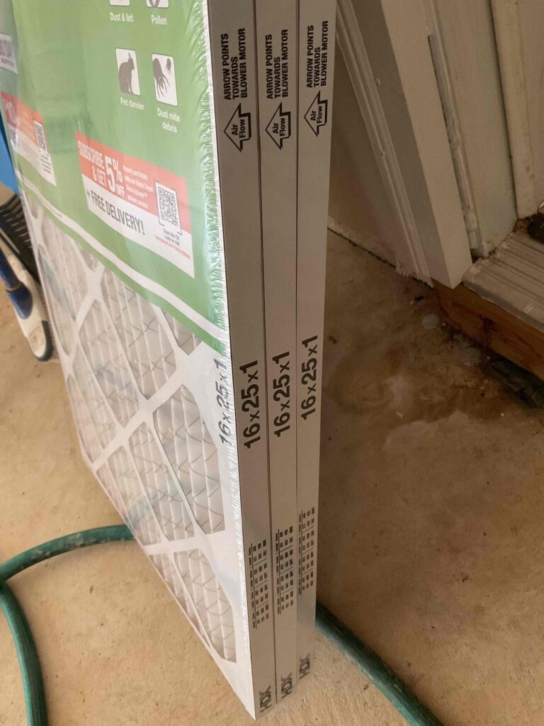 New 16x25x1 pleated air filters in their boxes, leaning against a wall before installation