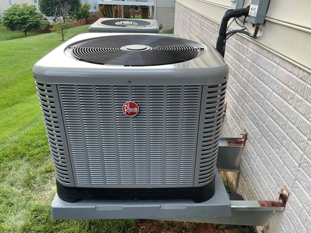 A Rheem condenser installed by SwiftPro on a bracket beside a brick Northern Virginia home.