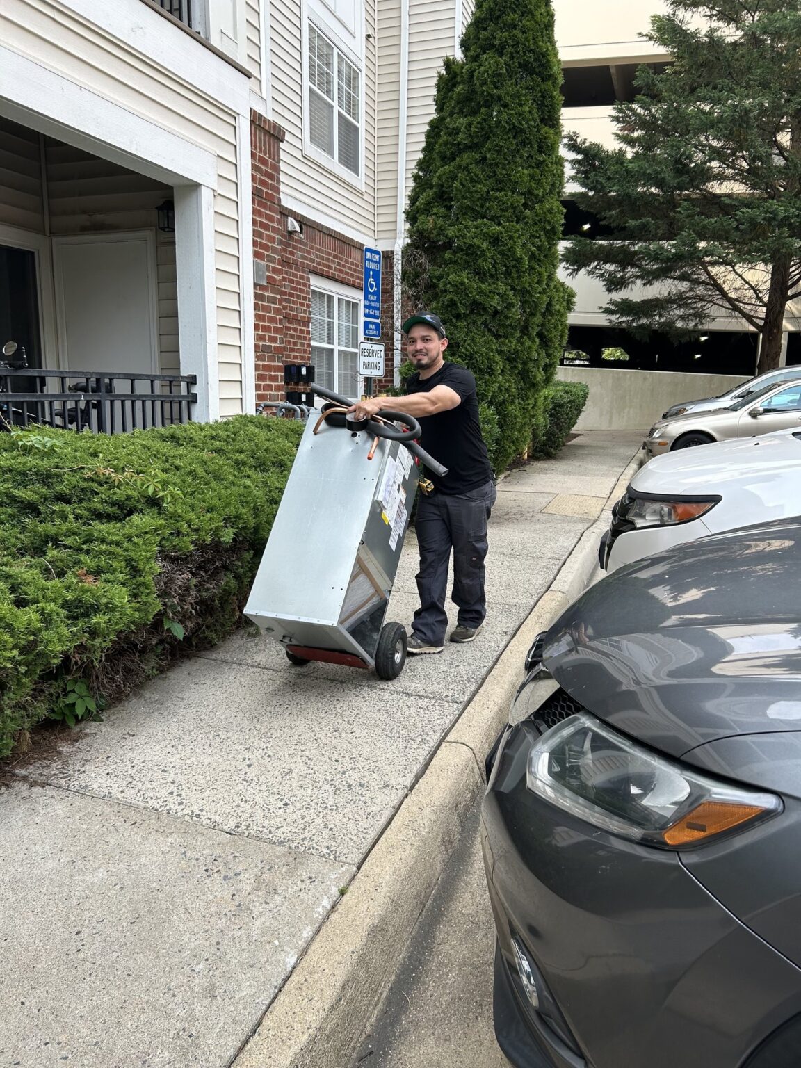 A SwiftPro technician wheeling new equipment on a hand truck up a driveway to a Northern Virginia townhouse