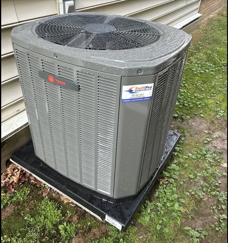 A new Trane outdoor unit SwiftPro installed on a level pad beside a Northern Virginia home, with a SwiftPro service sticker on its corner panel