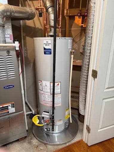 Residential water heater installed in a utility room with pipes and ventilation