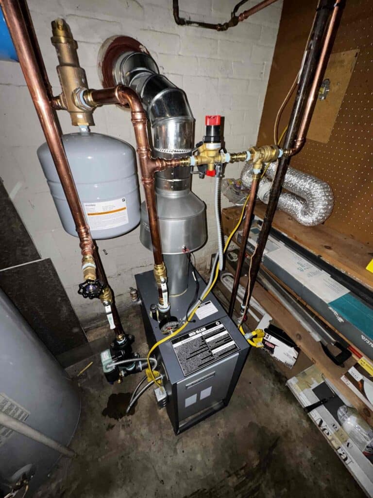 A hot water boiler installed by SwiftPro in a Northern Virginia basement, with a gray expansion tank, an automatic air vent and a fill valve on the copper piping and the vent connector running into the chimney