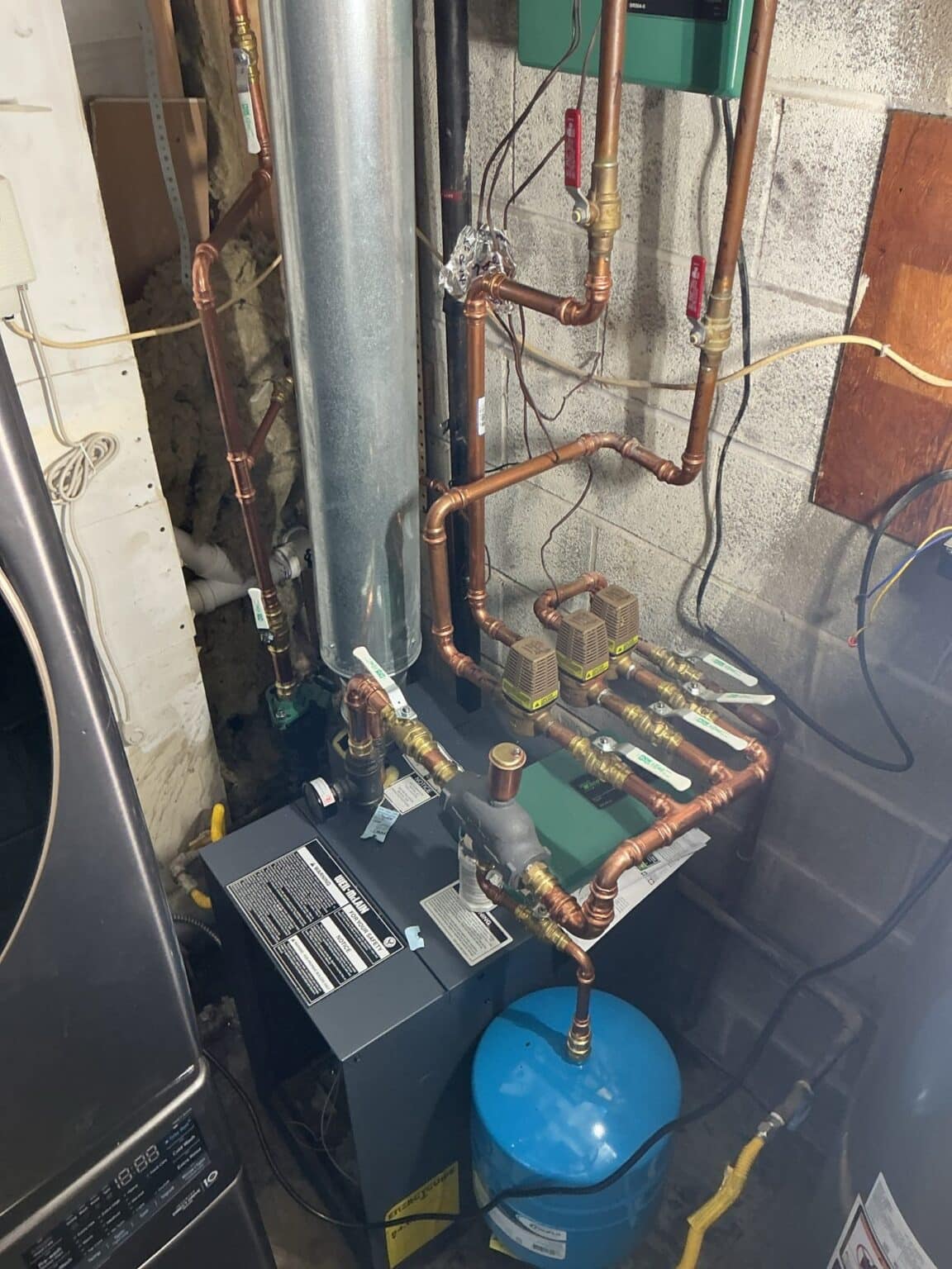 A SwiftPro boiler installation in a Northern Virginia utility room showing the new flue, the blue expansion tank and the rebuilt copper near-boiler piping