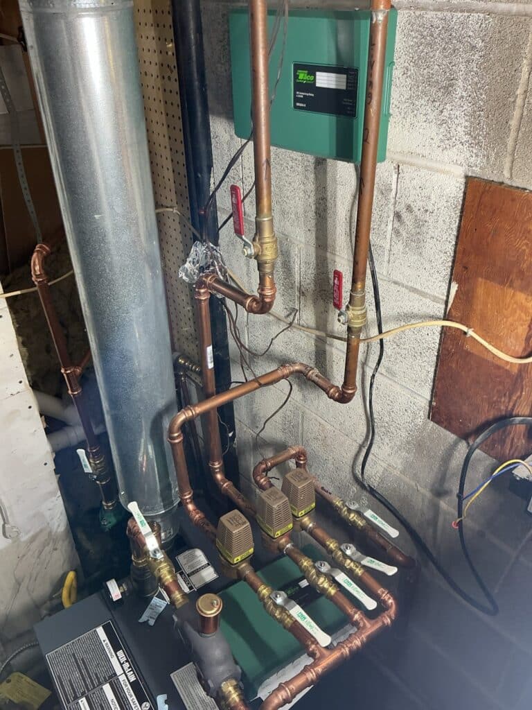 A new Weil-McLain gas boiler installed by SwiftPro in a Northern Virginia basement, with copper near-boiler piping, three Taco zone valves and a Taco zone relay on the block wall above it