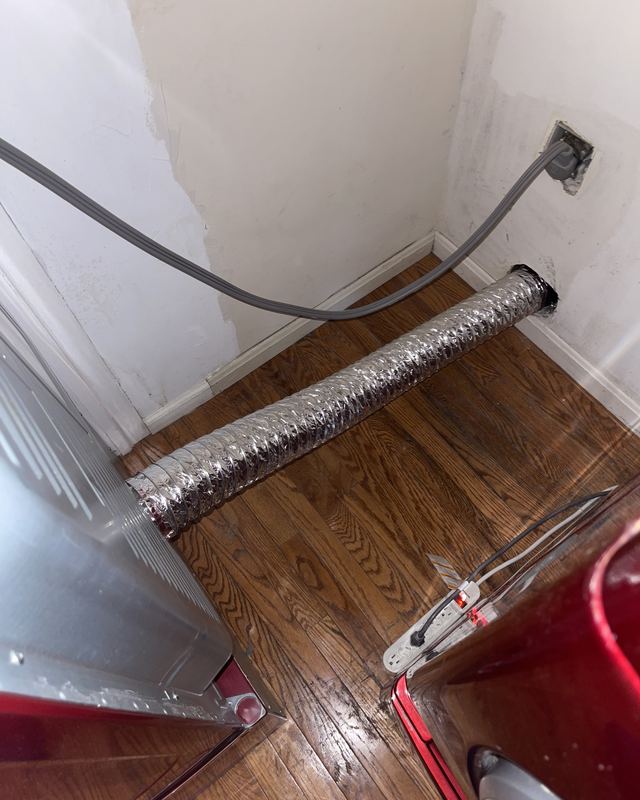 The same Ashburn laundry room after the SwiftPro dryer vent cleaning: a clean wall and a new hose connected to the vent
