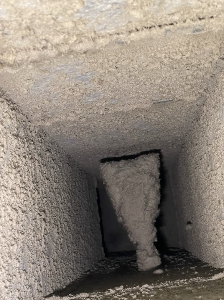 A branch takeoff inside a supply duct in a Northern Virginia home before cleaning, a wad of dust and lint hanging in the opening