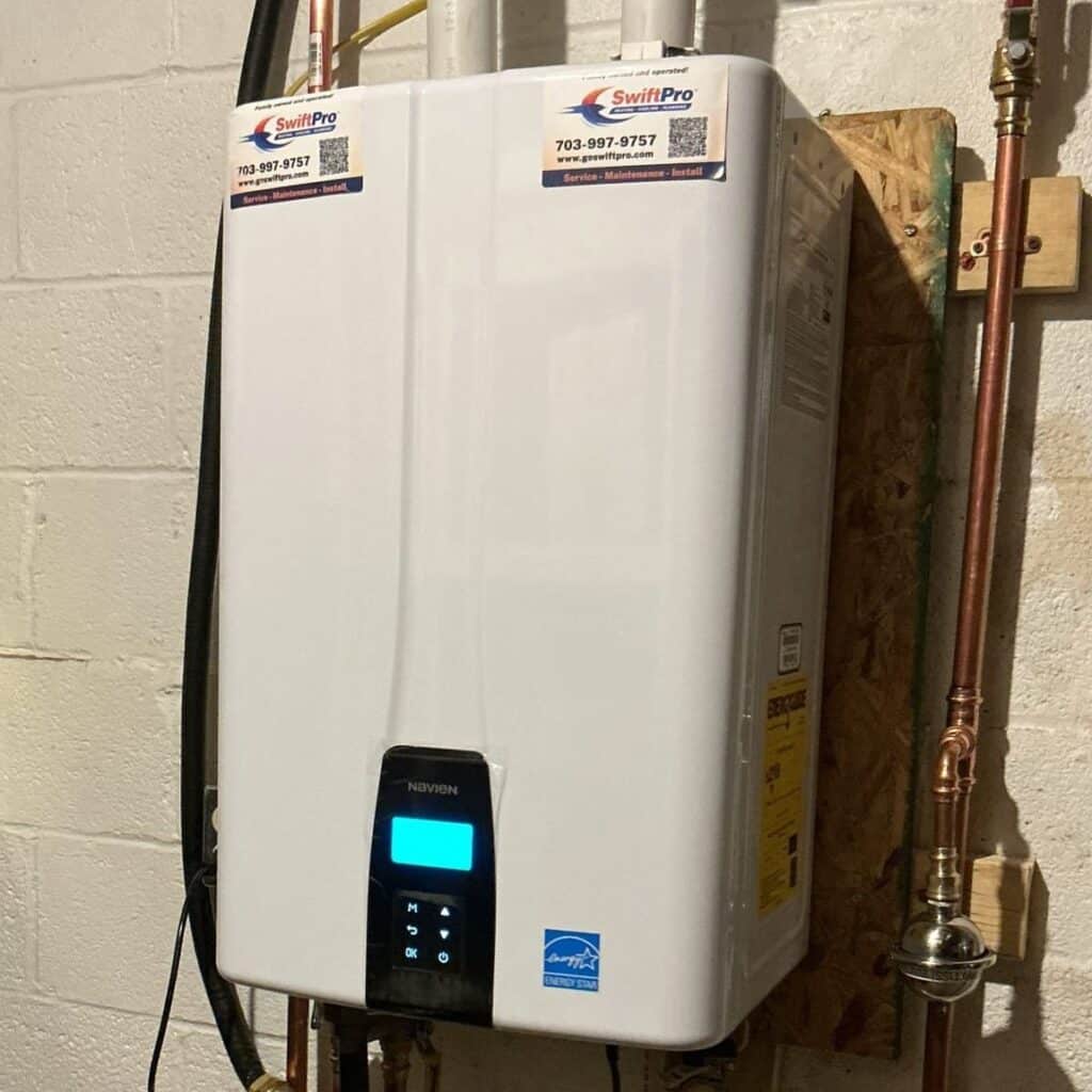 A Navien tankless water heater with two SwiftPro service stickers on top, mounted on a basement block wall in Northern Virginia