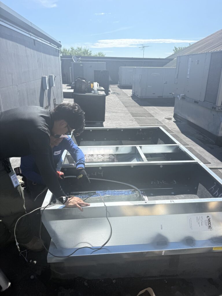 Two SwiftPro technicians working inside the curb of a new rooftop HVAC unit on a Northern Virginia commercial roof