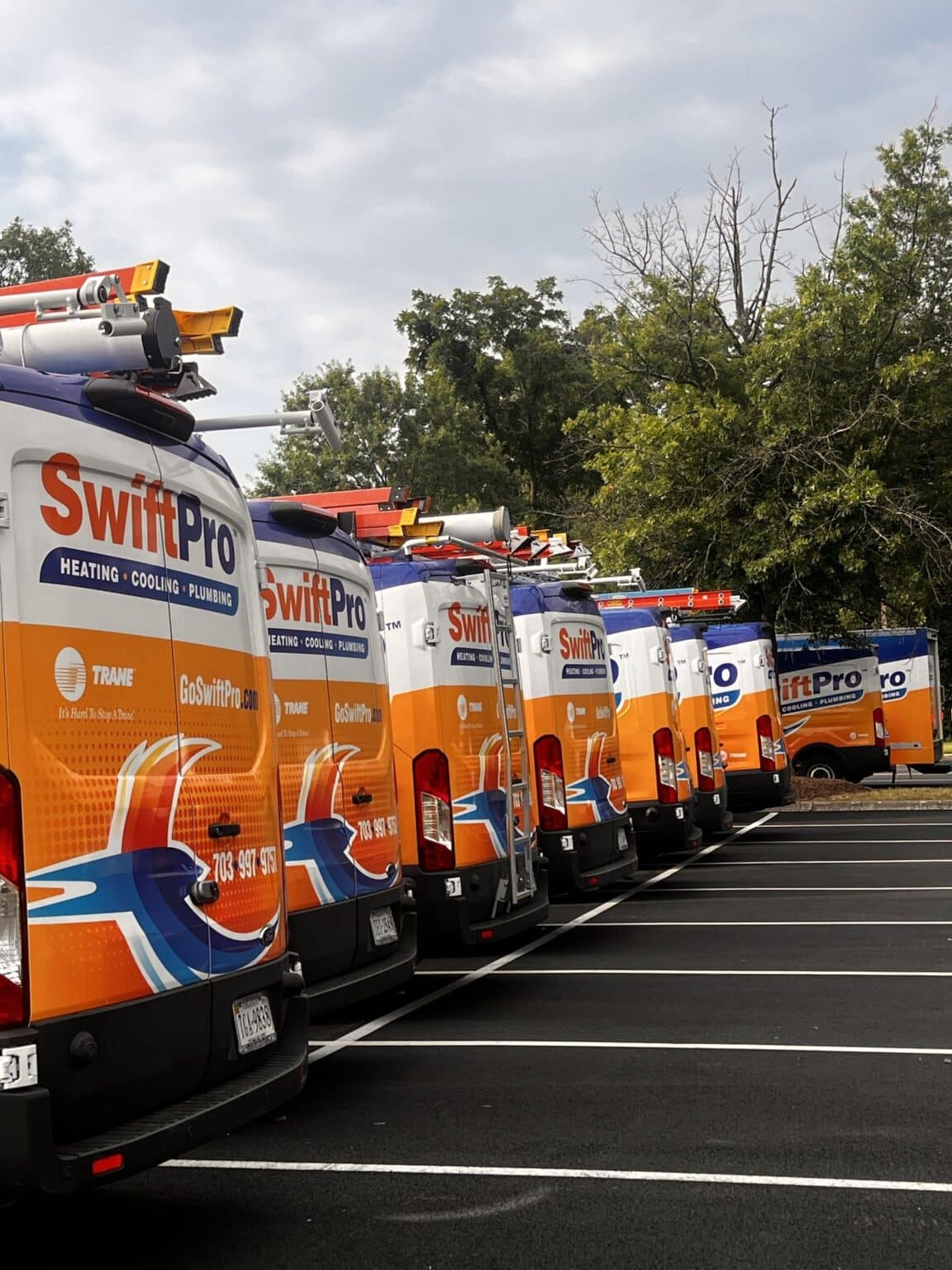 The back doors of a row of wrapped SwiftPro service vans, each carrying the Trane logo beside the SwiftPro name and phone number