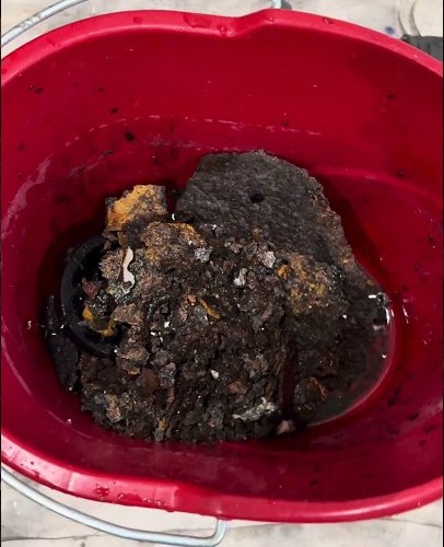 An old sump pump caked in rust and sludge, in a bucket after a SwiftPro plumber pulled it from the pit