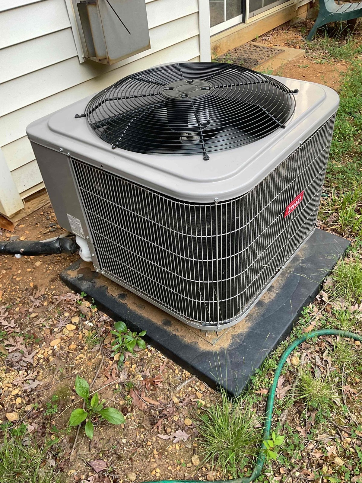 A Bryant air conditioner condenser on a rubber pad beside a vinyl-sided Northern Virginia house, on a SwiftPro service call