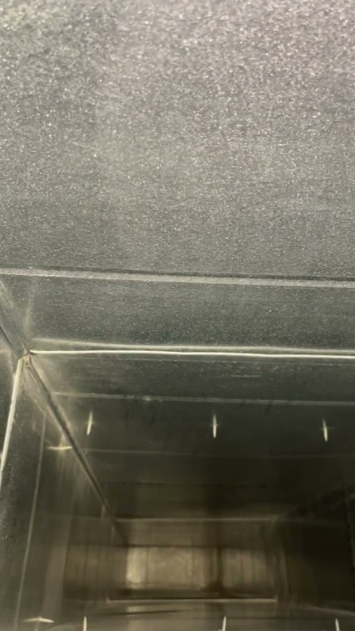 Raw phone clip, no text: a light pans around the inside of a clean sheet-metal plenum and down a trunk line.