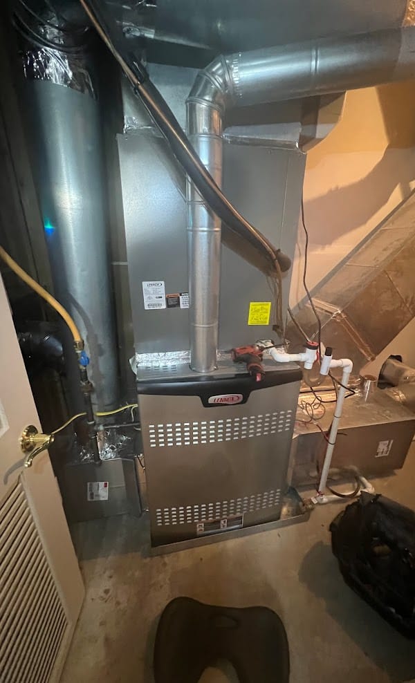 A Lennox gas furnace on a SwiftPro repair call in a Northern Virginia basement, the technician's drill resting on top of the cabinet beside the flue