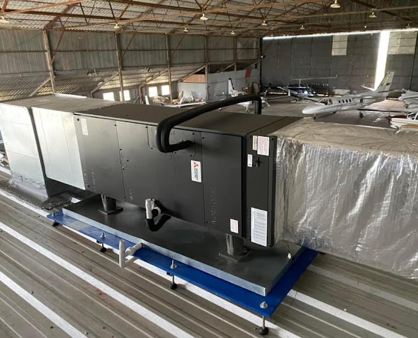 A Mitsubishi Electric unit set on rails above a metal roof inside an aircraft hangar, a SwiftPro commercial job in Northern Virginia