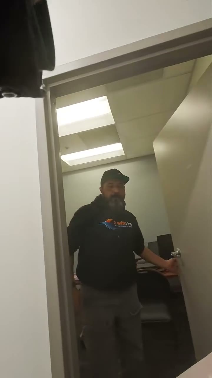 Someone walks Krispy Kreme donut boxes through the SwiftPro office for Employee Appreciation Day, offering them to office staff at their desks and to techs in SwiftPro hoodies, with each donut named o