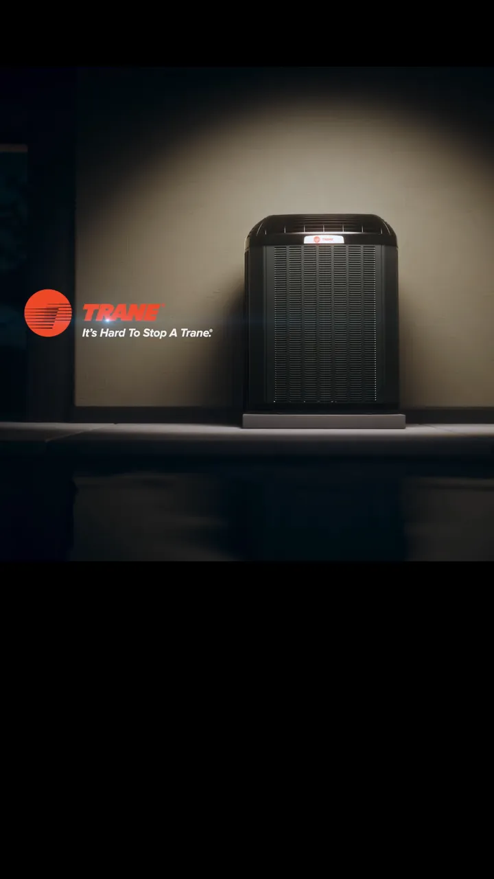 Trane's film: a Trane outdoor unit under a spotlight against a bare wall.