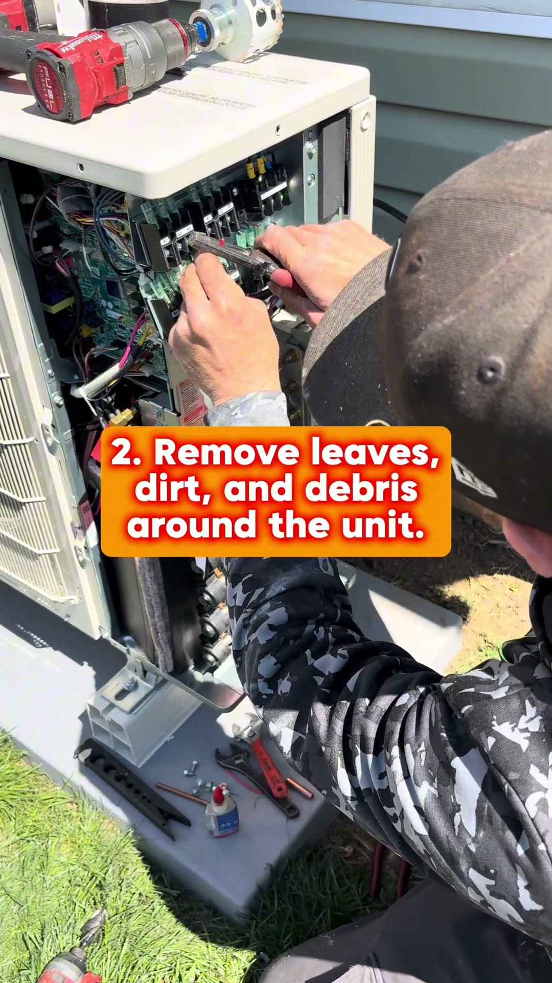 Mini split maintenance: a tech works under the eaves outside, a tech in a camo hoodie works on the outdoor mini split's control board with Milwaukee tools on the unit, and a tech on a ladder lifts the