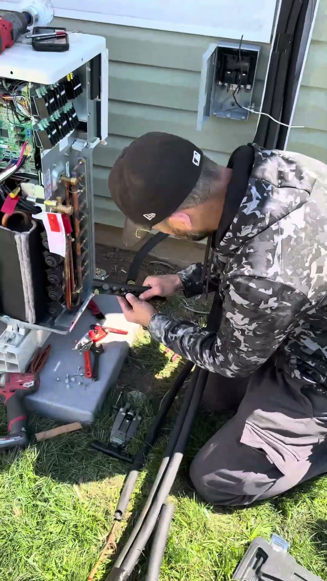 A young tech in a SwiftPro hoodie reacts while holding a yellow tool indoors, then a tech in a camo hoodie wires and connects line sets to an outdoor mini split condenser on the lawn.