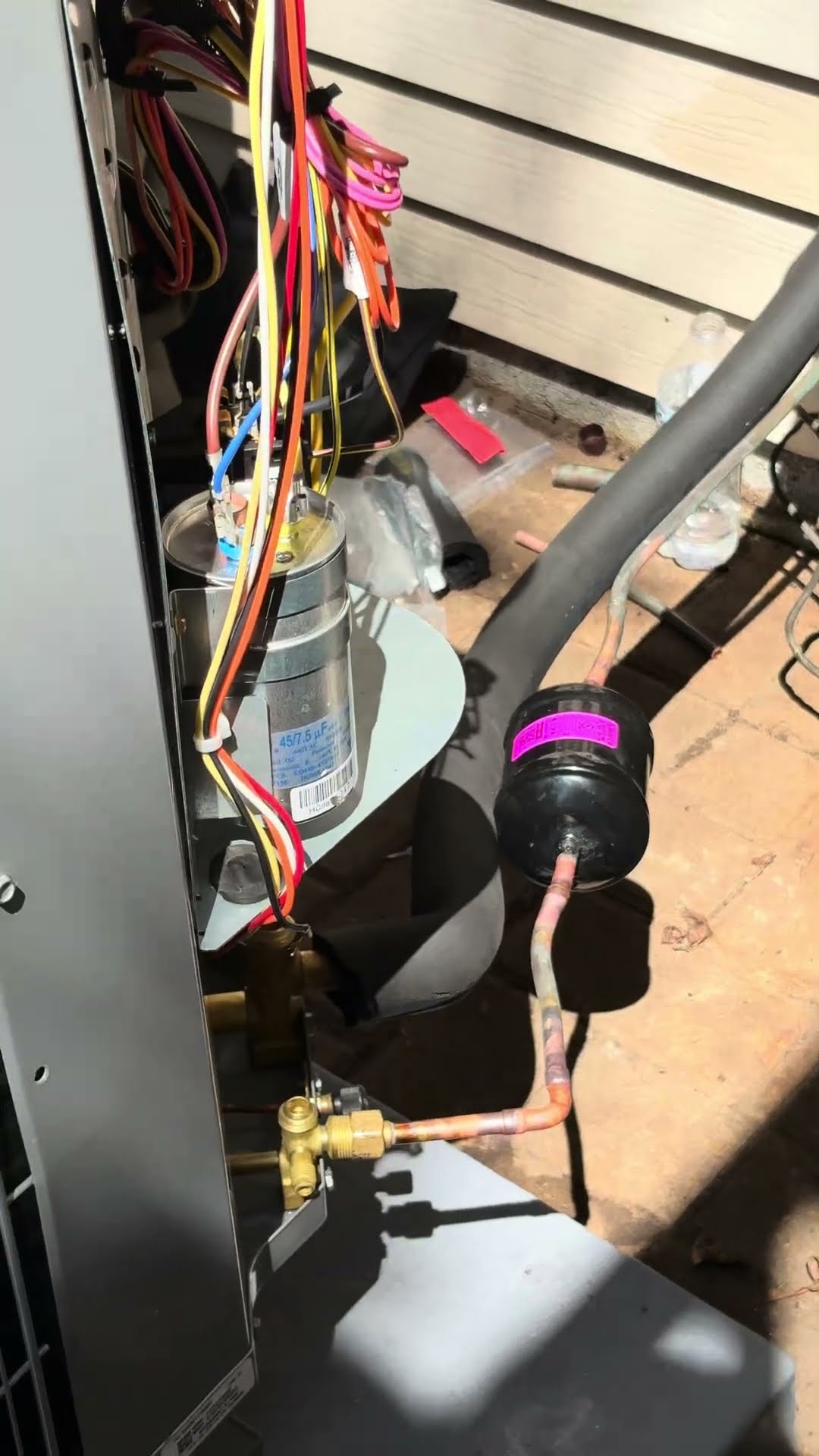 Close-up of an AC condenser's insides: capacitor, wiring, filter drier and service valve.
