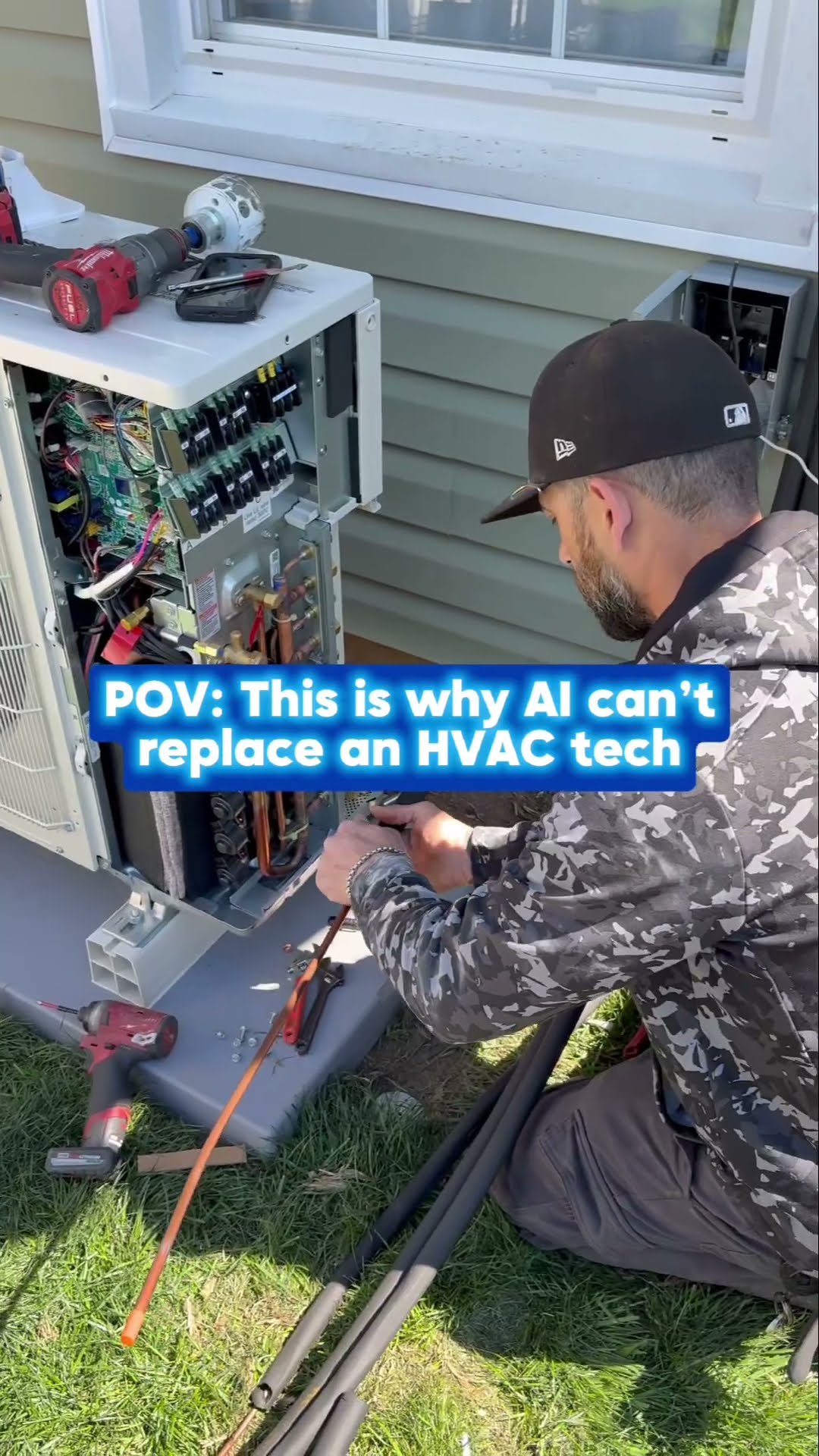 Caption joke that AI cannot replace an HVAC tech, over job footage: a bearded tech in a camo jacket wires an opened mini-split outdoor unit, copper and gas piping is fitted under a wall-hung tankless