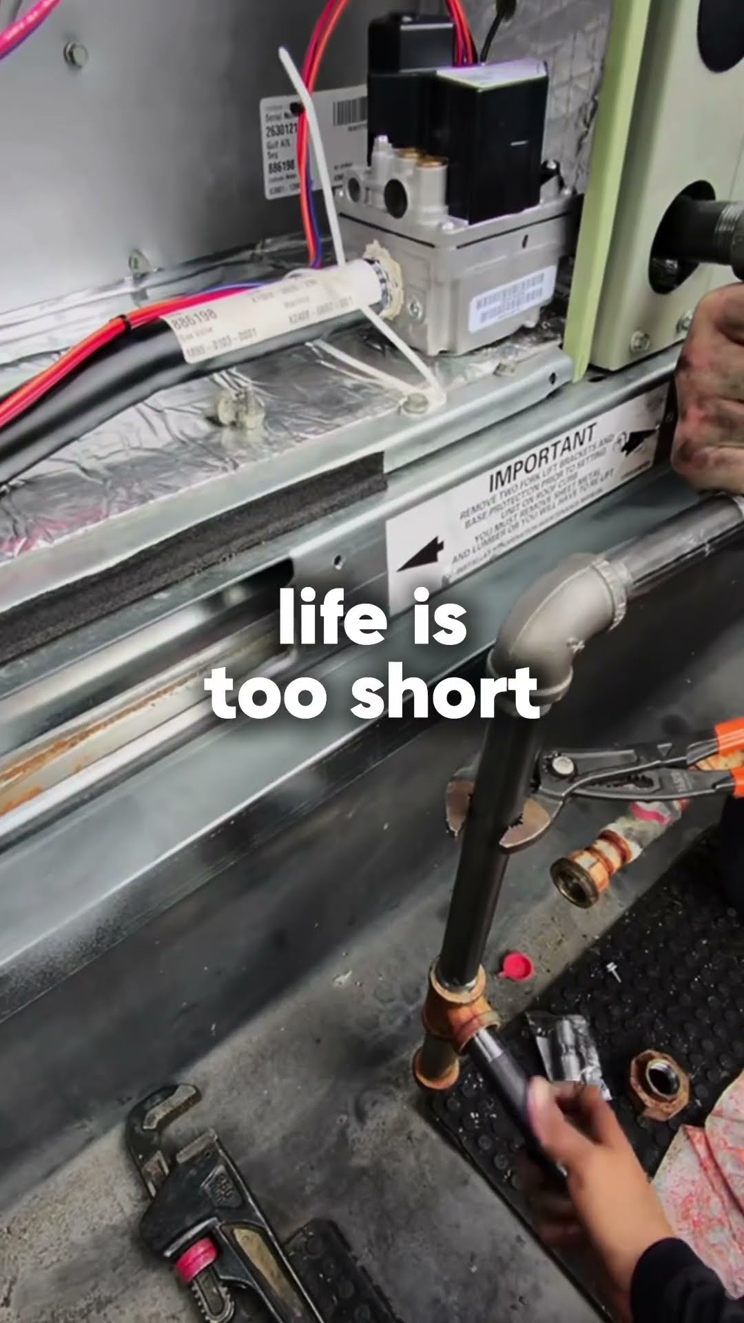 POV gloved hands working inside a gas furnace or packaged unit: sheet metal panel, gas valve and burner area, gas pipe with a pipe wrench.