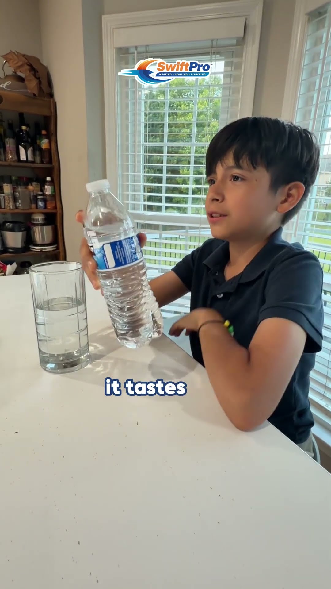 A boy at a kitchen table compares a glass of tap water with bottled water and rates the taste.