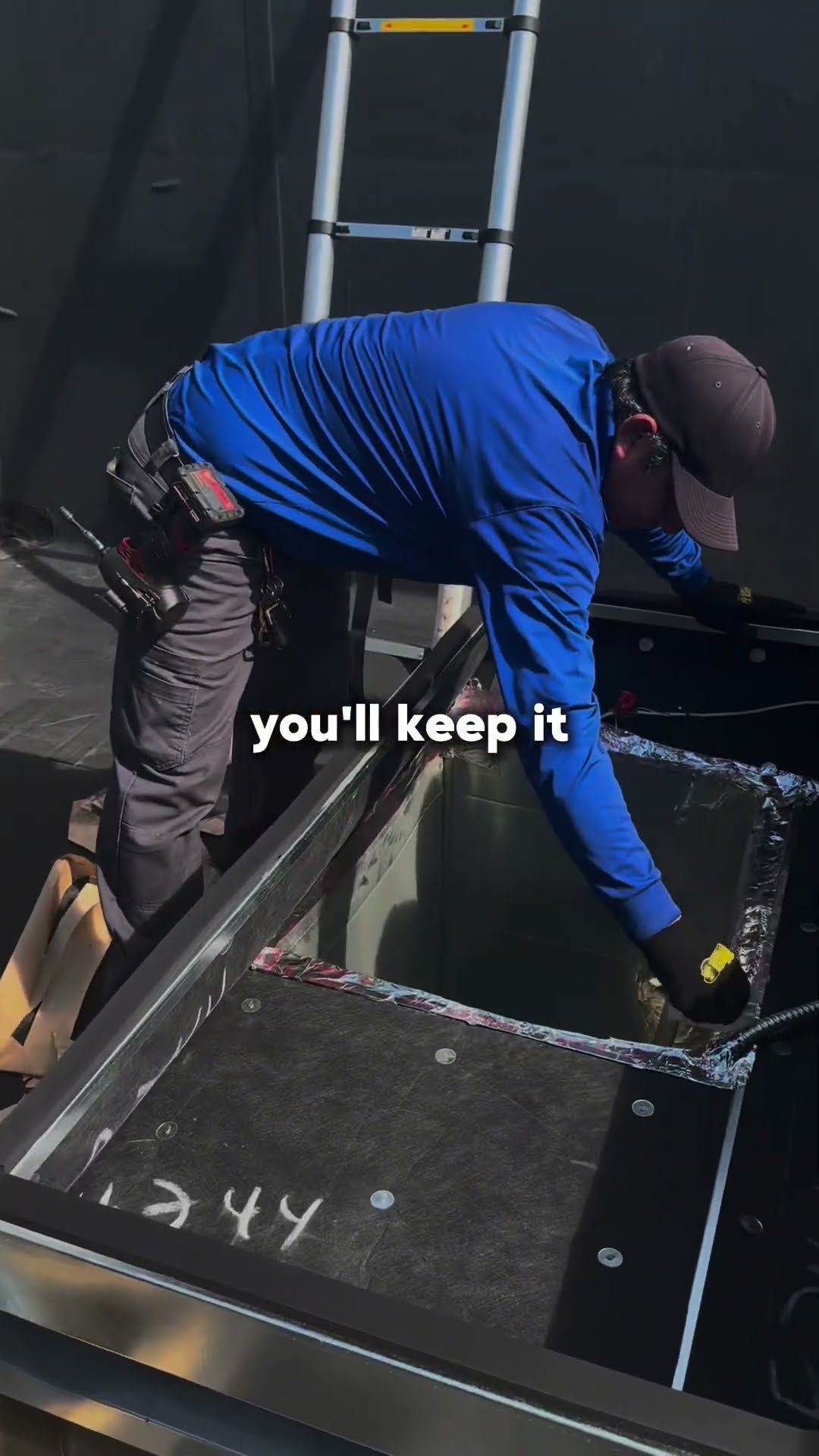 Commercial rooftop job: a roof curb adapter lifted by crane straps from a flatbed trailer in a parking lot, then two techs fitting and sealing the curb on a roof.