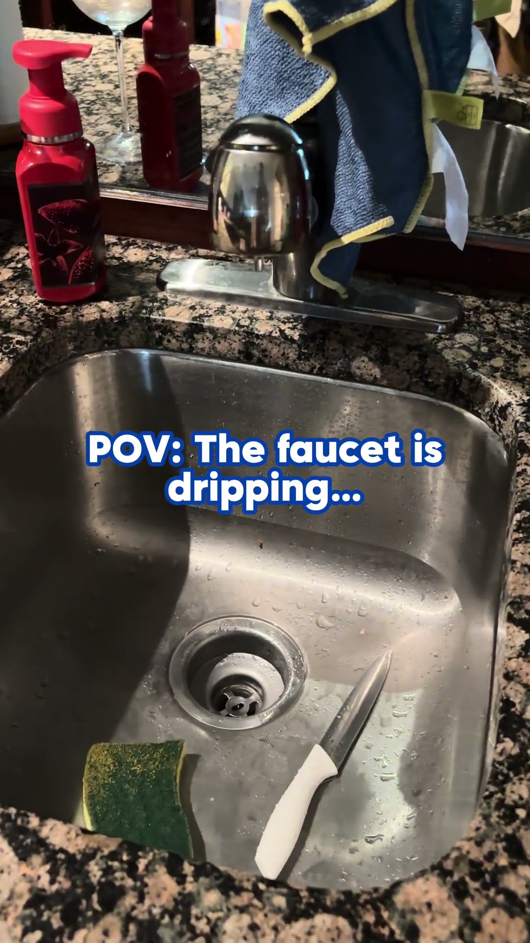 A kitchen faucet drips into a stainless sink on a granite countertop, with the caption the faucet is dripping.