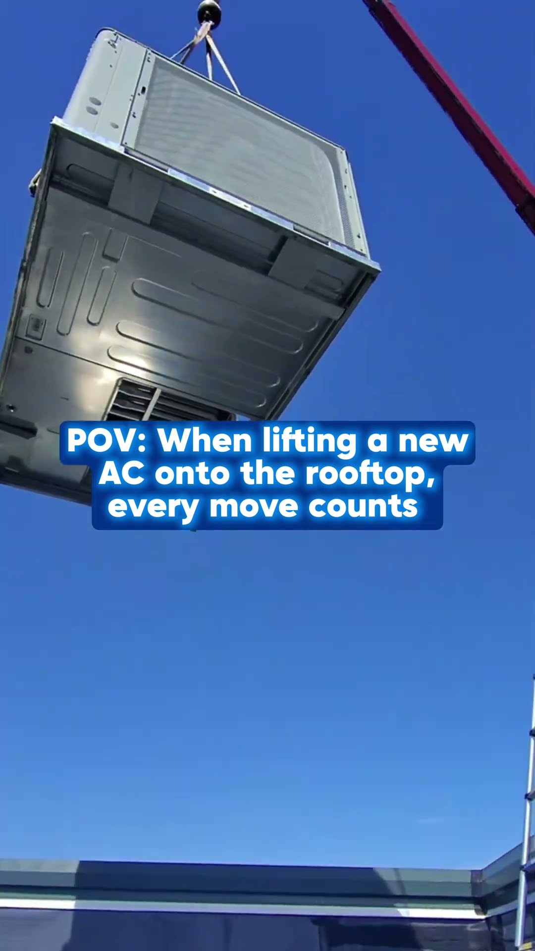 A crane lifts a new rooftop AC package unit against blue sky over a brick commercial building.