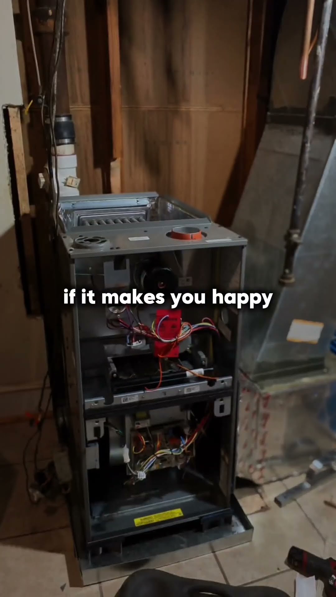 Basement furnace install with the front panels off showing wiring and inducer; a tech in black shirt and olive pants walks past.