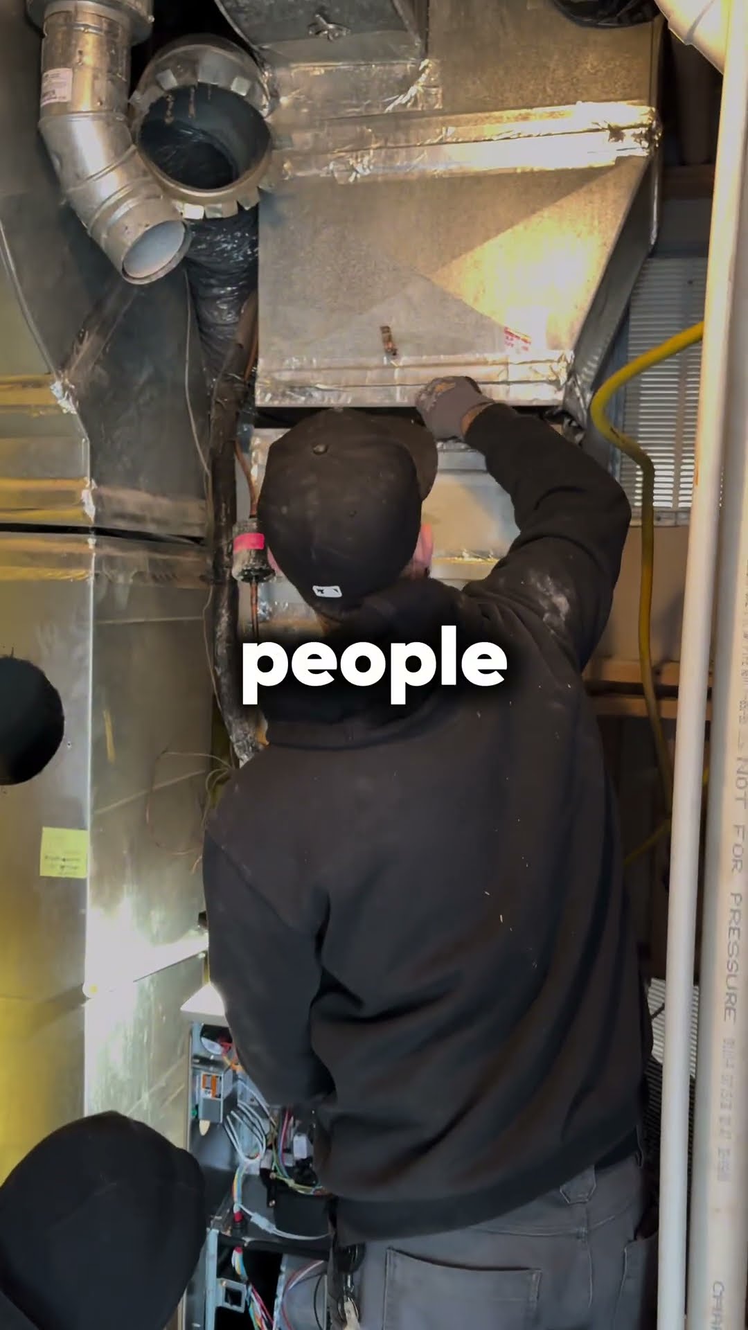 Motivational text over job footage: a tech in a black cap and hoodie reaches into a furnace evaporator coil cabinet, two techs move an AC condenser on a hand truck across a brick patio beside a house,