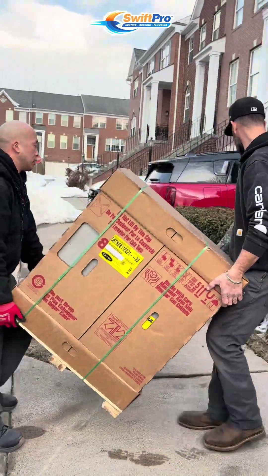 An old gas furnace with its panels off in a closet, then two techs carry a boxed new furnace up a snowy townhouse sidewalk and a bald tech and a bearded tech wire it in.