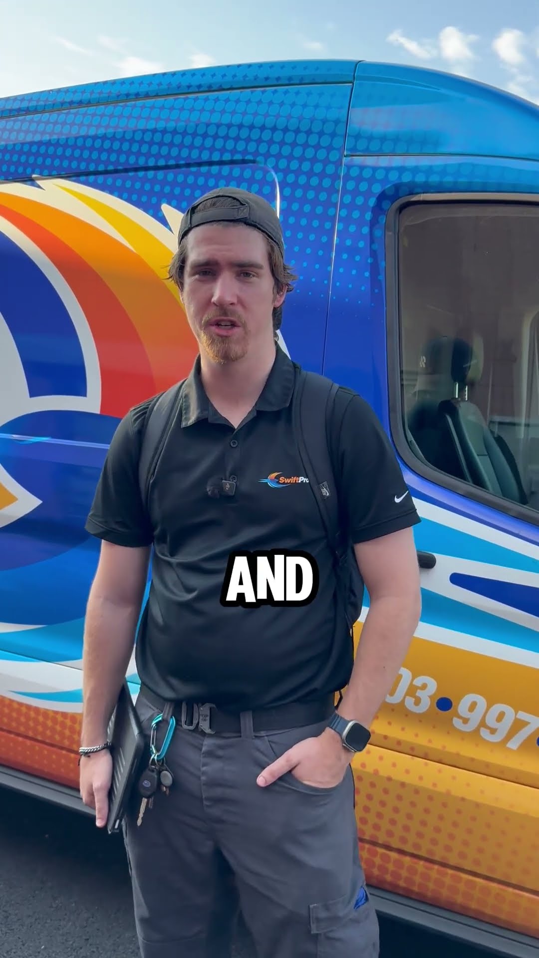 A young tech in a black SwiftPro polo, backwards cap and backpack stands in front of the wrapped SwiftPro van holding a tablet and talks about a time he made a real difference for a customer.