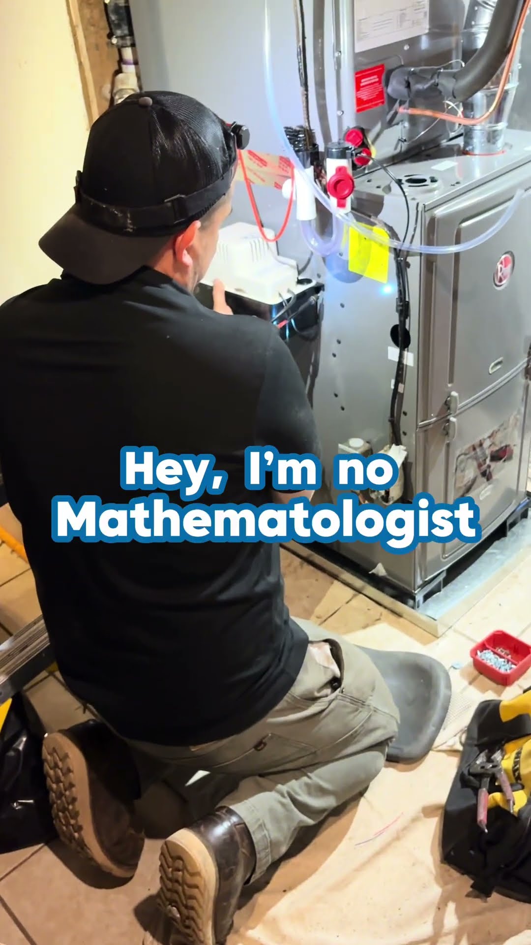A tech kneels at an open gas furnace with a condensate pump in a basement.