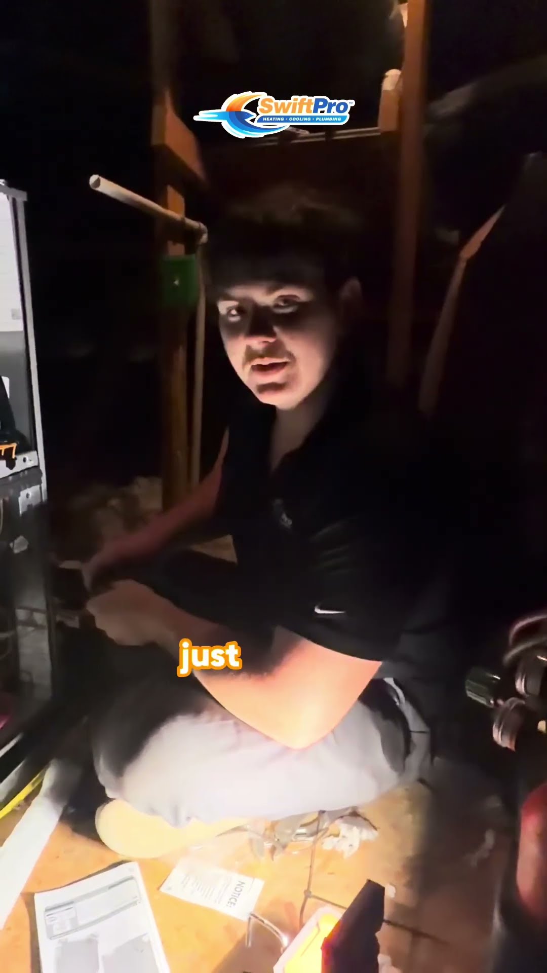 A young tech in a black polo sits in an attic beside an open furnace with wiring, telling the camera about moving from the Marine Corps to HVAC.