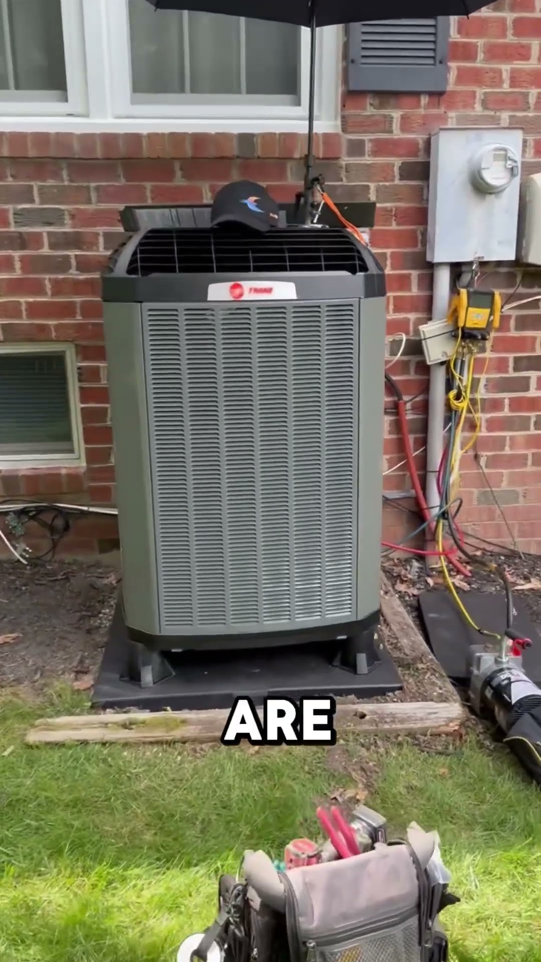A SwiftPro van parked in a driveway with its doors open, then a new Trane outdoor AC condenser (Trane badge legible) on a pad against a brick house, with the disconnect, new wiring and gauge hoses att
