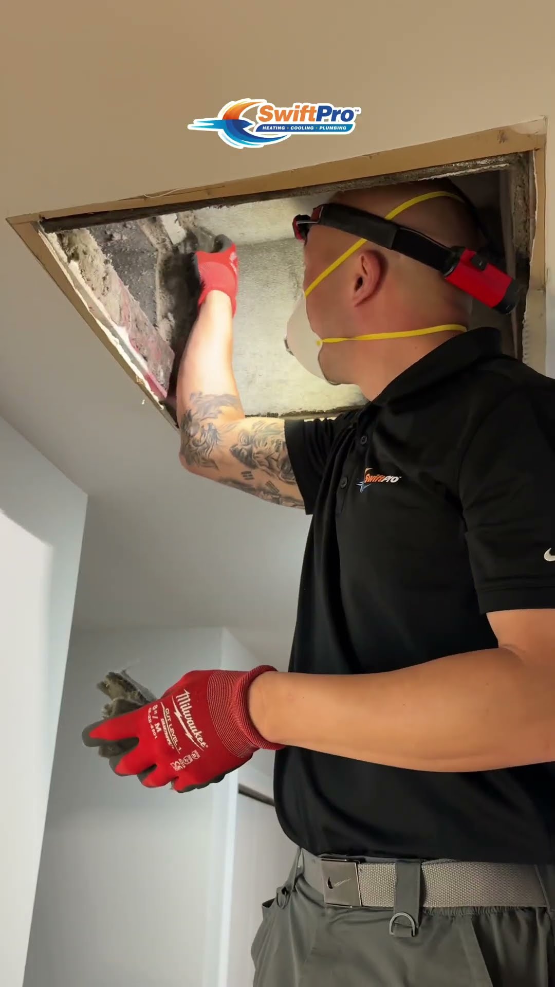 A duct cleaning tech in an N95 mask and red headlamp cleans an open ceiling duct opening in a hallway, then blows it out with an XPOWER blower.