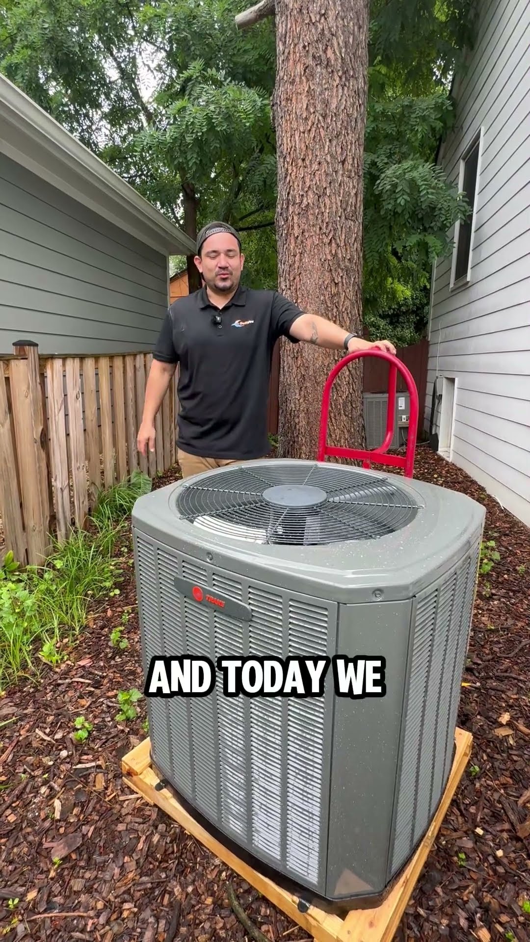 A tech introduced as Moises stands behind a new Trane outdoor AC condenser (Trane badge legible) on a wooden pallet in a side yard, with a red hand truck, and explains today's AC replacement.